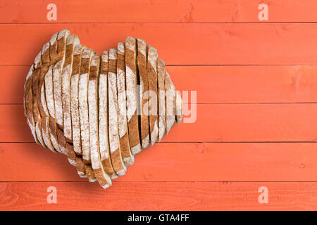 Vue d'en haut sur delicious tranches de pain en forme de coeur sur table en bois peint avec la surface des panneaux orange et copy space Banque D'Images