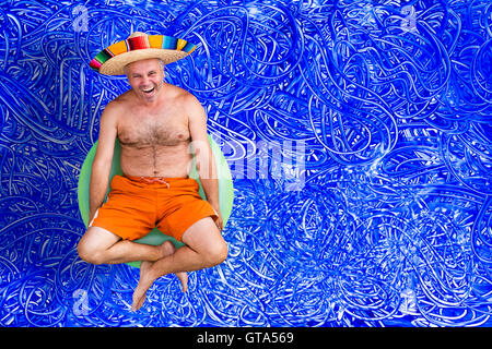 Heureux homme d'âge moyen sur les vacances d'été assis dans son maillot et sombrero sur un tube vert de rire jusqu'à l'appareil photo Banque D'Images