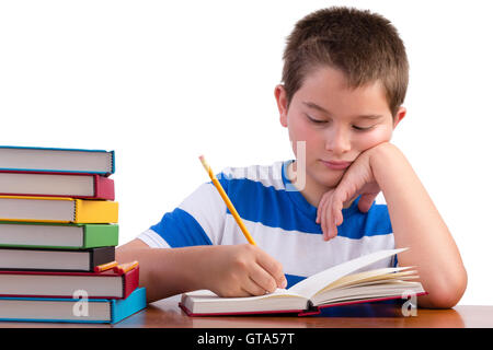 Les jeunes de l'école intermédiaire dédié à l'étude pour enfants de sexe masculin d'un bureau avec une pile de manuels colorés avec lui, comme il l'écrit pas Banque D'Images