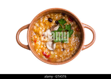 Vue aérienne de la soupe aux légumes et haricots cuits dans un pot en argile sur un fond blanc. Banque D'Images