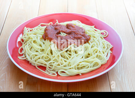 Garniture sur Marinara pâtes spaghetti cuits dans la plaque ronde en céramique sur table en bois lisse Banque D'Images