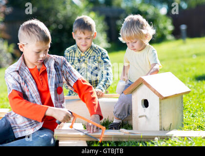 Happy kids frères décisions wooden birdhouse par des mains Banque D'Images