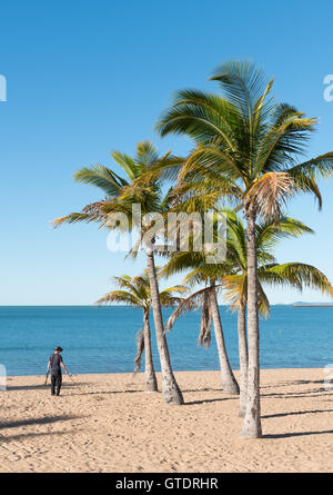 L'homme à l'aide de détecteur de métal sur belle plage tropicale sur le Strand, Townsville, Australie avec ciel bleu et la mer Banque D'Images