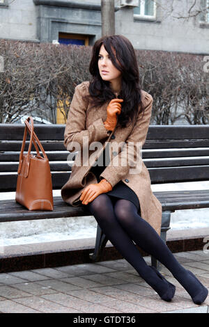 La belle ville jeune femme assise sur un banc Banque D'Images