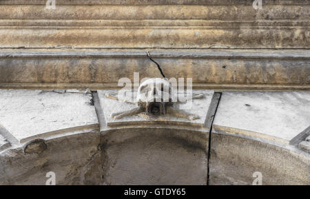 Un crâne de pierre placé près de l'entrée d'un charnier, dans un cimetière. Banque D'Images