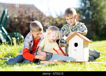 Happy kids wooden birdhouse par les mains. Enfant plus âgé enseigne à son jeune frère. Banque D'Images