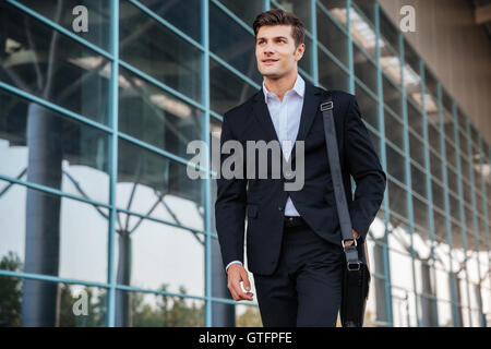 Portrait of a happy handsome businessman la marche à l'extérieur de la ville Banque D'Images
