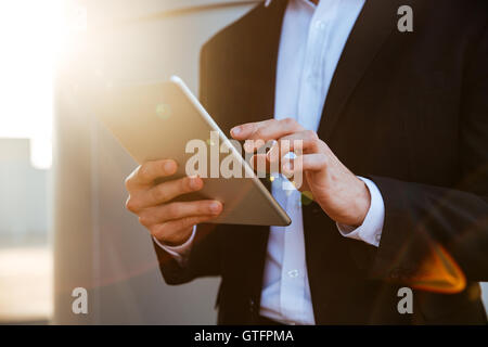Portrait d'un jeune businessman in suit holding tablet pc outdoors Banque D'Images