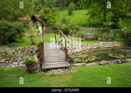 Un pont de bois sur un étang dans un jardin en été Banque D'Images