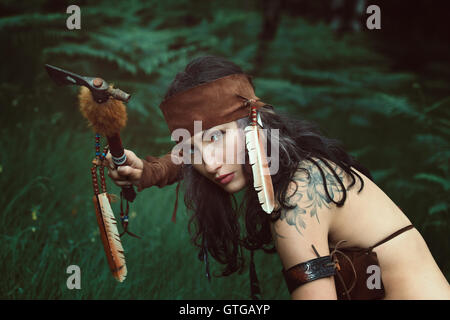 Belle American Indian chasseresse avec tomahawk . Portrait en extérieur Banque D'Images