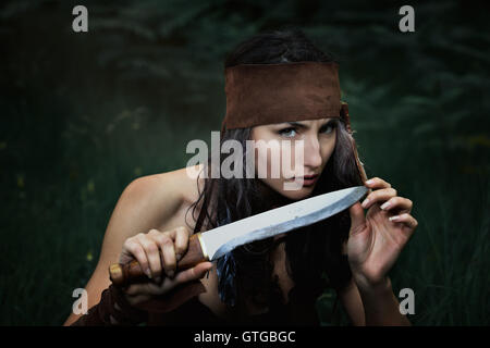 American Indian hunter jouer avec un couteau . Regard dangereux Banque D'Images