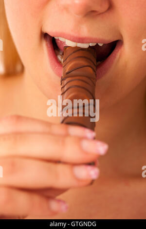 Belle jeune femme mange isolés chocolat over white background Banque D'Images