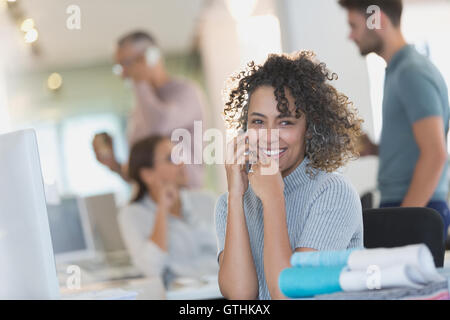 Smiling businesswoman talking on cell phone in office Banque D'Images