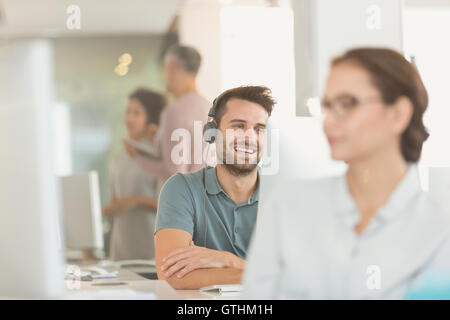 Smiling businessman créative avec des écouteurs vidéoconférence à computer in office Banque D'Images