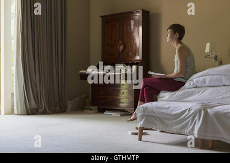 Pensive woman reading lettre on bed Banque D'Images