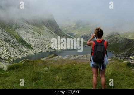 Gorgeous woman de prendre des photos d'un beau lac glaciaire caché entre les montagnes, Piémont, Italie. Marco Imazio © Banque D'Images