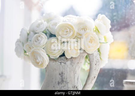 Art et artisanat shabby chic Imitation de roses blanches dans un pichet blanc. Banque D'Images