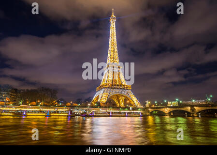 Paris, France - 14 Février 2016 : La Tour Eiffel, des feux d'or dans la nuit, ce qui se reflète dans la Seine de l'eau. Banque D'Images