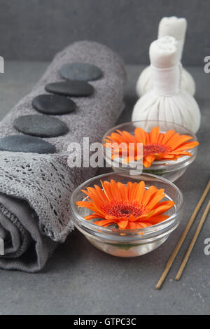 Spa Massage avec une serviette roulée, thai herbal compress balls et des fleurs sur la surface gris Banque D'Images