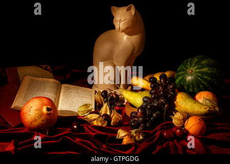 Thème classique de la vie toujours avec des fruits, réserver et statue d'un chat. Le style pictural de l'alimentation et de l'étude des antiquités. Banque D'Images