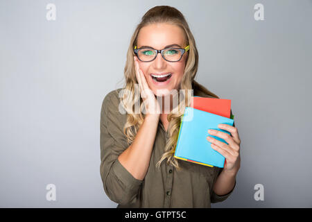 Heureux l'étudiant excité fille avec surprise l'expression du visage sur fond gris, profitant des premiers jours dans l'université Banque D'Images