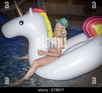 Orange County, Californie, USA. 3e, 2016 Sep. Une jolie jeune femme blonde portant un bikini et trucker cap se trouve sur un inflaitable licorne flottant dans une piscine la nuit. © David Bro/ZUMA/Alamy Fil Live News Banque D'Images