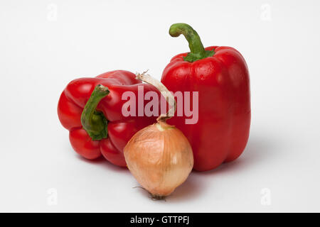 Deux poivrons rouges et un oignon de couleur brun contre l'arrière-plan blanc. Les légumes et les ingrédients alimentaires. Le piment doux et peu Banque D'Images