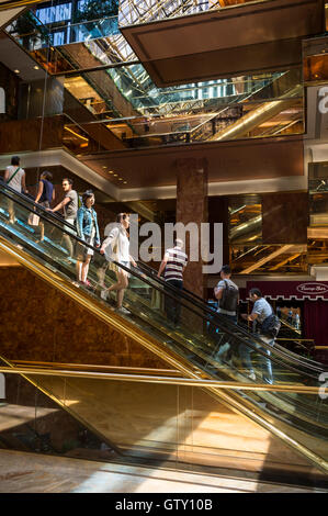 NEW YORK - 3 septembre 2016 : les visiteurs monter les escaliers mécaniques en laiton en miroir dans l'atrium de marbre rose la Trump Tower. Banque D'Images