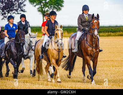 Un groupe de cavaliers à cheval à travers un champ de chaumes en automne Sunshine Banque D'Images