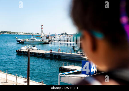 Jeune fille âgée de 10 est à la recherche sur le petit port de Cannes, France. Elle est au départ de l'île de Lérins lors d'une journée d'été. Banque D'Images