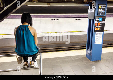 New York City,NY NYC Lower Manhattan,quartier financier,Fulton Center,métro,station,MTA,plate-forme,adultes,femme femme femme,assis sur la rambarde,r Banque D'Images