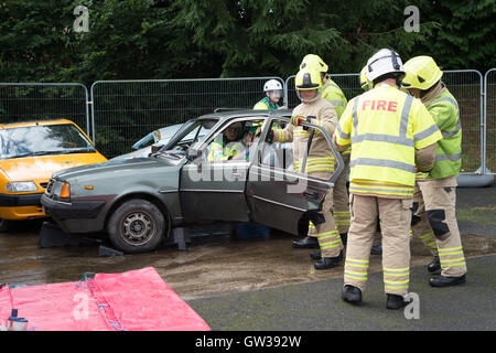 Les hommes de feu simuler un accident de voiture en coupant les portes de sauvetage au large de la voiture. Banque D'Images