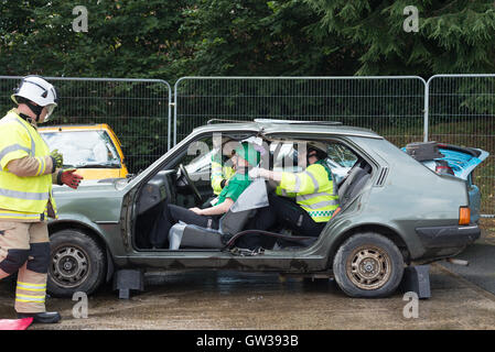 Les hommes de feu simuler un accident de voiture en coupant les portes de sauvetage au large de la voiture. Banque D'Images