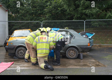 Les hommes de feu simuler un accident de voiture en coupant les portes de sauvetage au large de la voiture. Banque D'Images