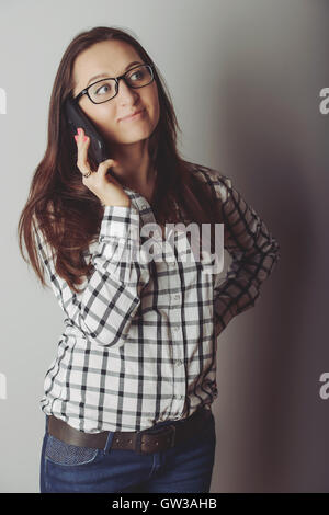 Happy brunette girl talking via smartphone à la maison Banque D'Images
