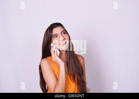 Portrait of Hispanic / jeune femme de race blanche à l'aide d'un téléphone mobile. Femme parlant au téléphone, isolés sur brackground gris. Banque D'Images