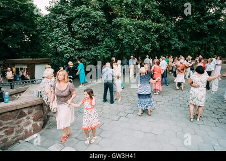 Mid adult Woman avec une jeune fille d'âge élémentaire passant par la danse de couples de personnes âgées sur la piste de danse en plein air en été Banque D'Images