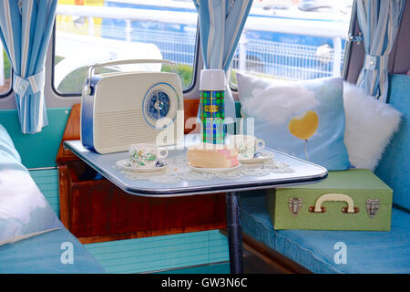 Intérieur de la fourgonnette VW Camper, avec table pour le thé de l'après-midi, avec gâteau de batten-burg, thermos ballon et radio rétro. Banque D'Images