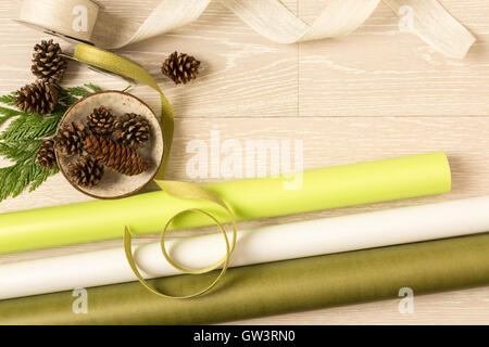 Les vacances de Noël vert et blanc du papier cadeau, de rubans et des pommes de pin sur fond en bois blanc rustique Banque D'Images