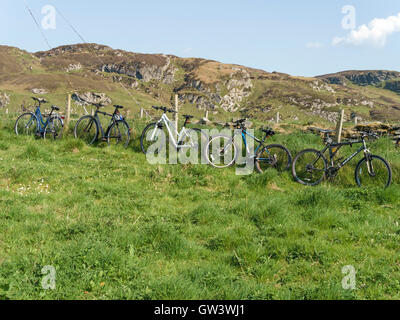 Rangée de cinq vélos de montagne leaning against fence, Kiloran, à l'île de Colonsay, Ecosse, Royaume-Uni. Banque D'Images