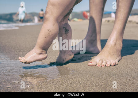 La mère et l'enfant marche pieds sur le sable plage pour première fois Banque D'Images