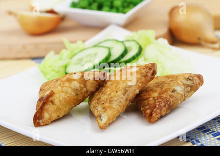 Samosas Indiens trois avec salade verte sur plaque blanche sur la surface en bois Banque D'Images