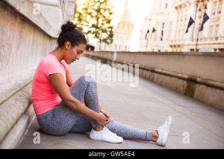 Jeune femme sentant son cheville douloureuse après l'exercice Banque D'Images