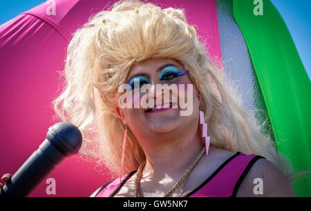 Drag Queen dans le costume et la perruque habillé pour un défilé de carnaval avec microphone Banque D'Images