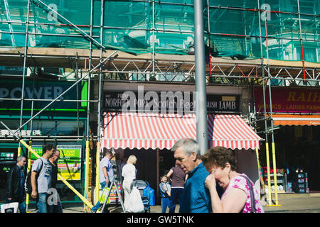 Shoppers walking down Walthamstow High Street, avec les bouchers en arrière-plan. Banque D'Images