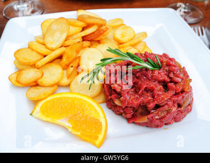 Tartare de boeuf haché cru la viande servie avec frites croustilles et décorées avec l'orange et au romarin Banque D'Images