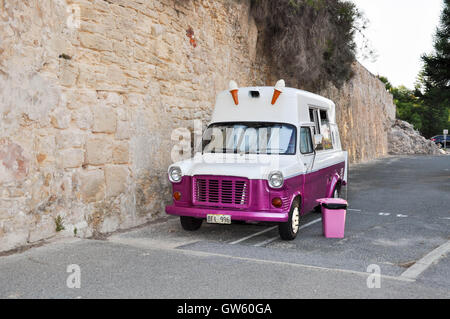 Retro chaud rose et blanc crème glace van avec poubelle rose garée le long d'un mur en pierre calcaire à Fremantle, Australie occidentale. Banque D'Images