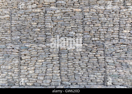 Le mur de pierres de rivière emballées dans une grille métallique Banque D'Images