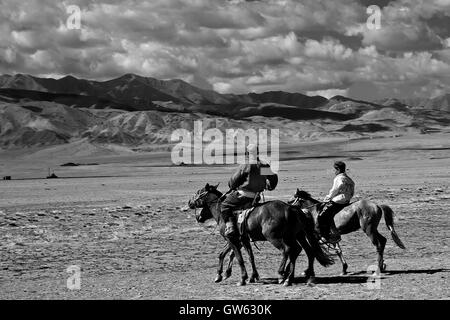 Père et fils à cheval retour à la maison, après la course de chevaux, partie de l'Naddam Festival, dans la région des montagnes de l'Altai, Mongolie Banque D'Images