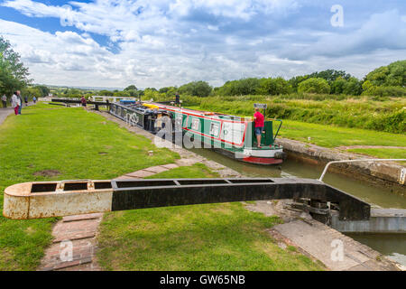 Barges colorées en passant par l'un des 16 Caen Hill locks sur le canal Kennet & Avon nr Devizes, Wiltshire, England, UK Banque D'Images